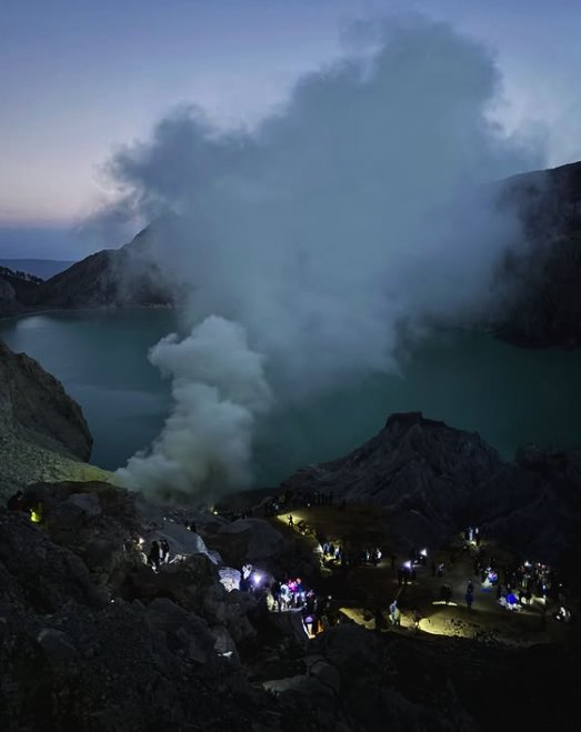 Headlamps strung out along the trail below the crater in the dark before dawn