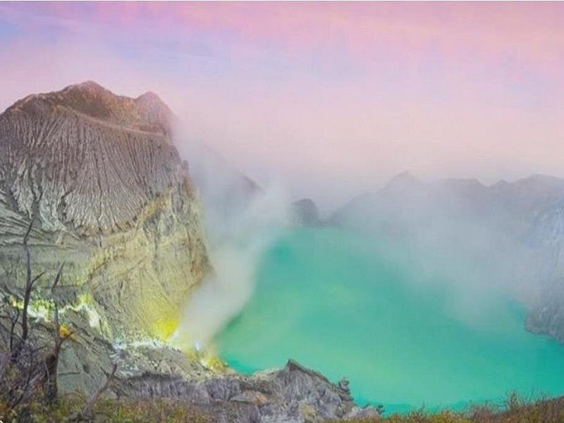 Sulfur steam blowing across the crater basin as the sky lightens behind the rim