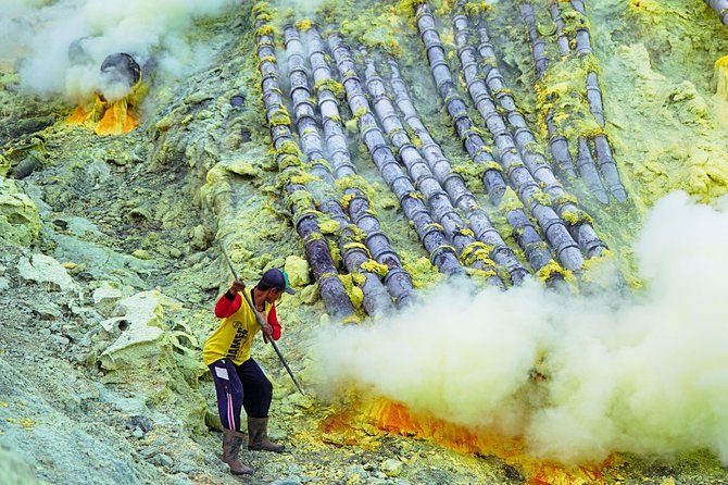 Miners loading yellow sulfur into paired baskets beside the steaming vents